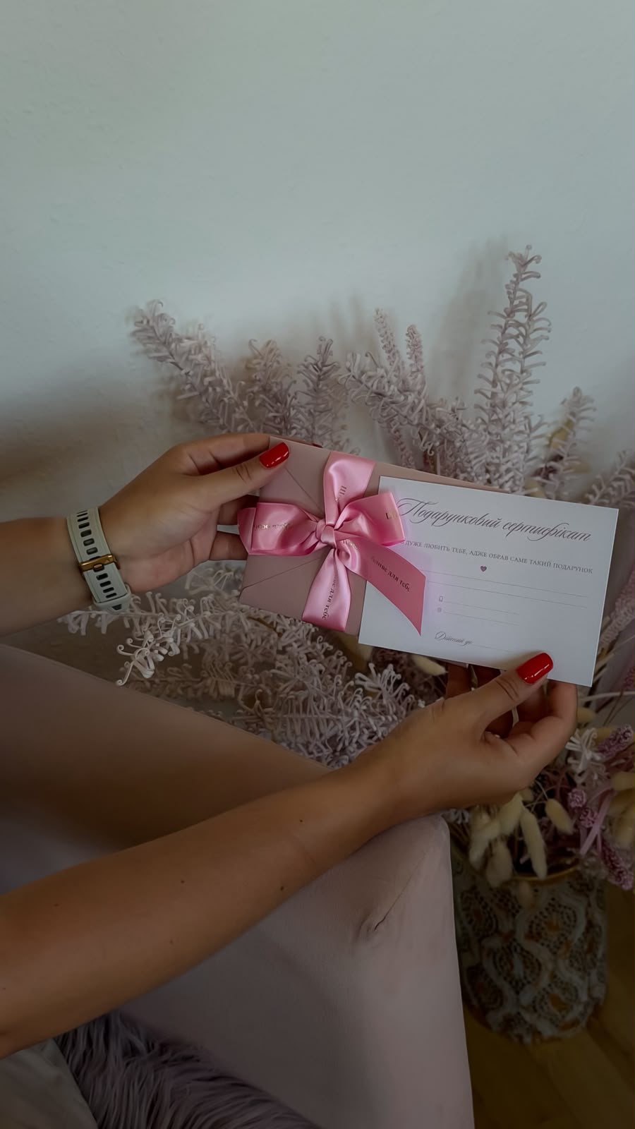 Gutschein mit Geschenkschachtel und rosa Schleife in den Händen