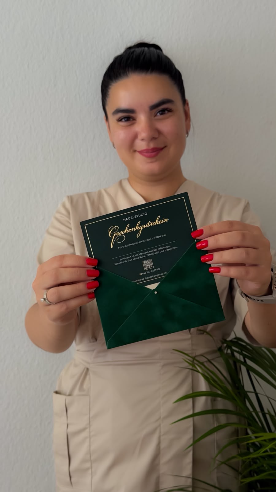 Karina hält einen dunkelgrünen Geschenkgutschein mit Goldschrift