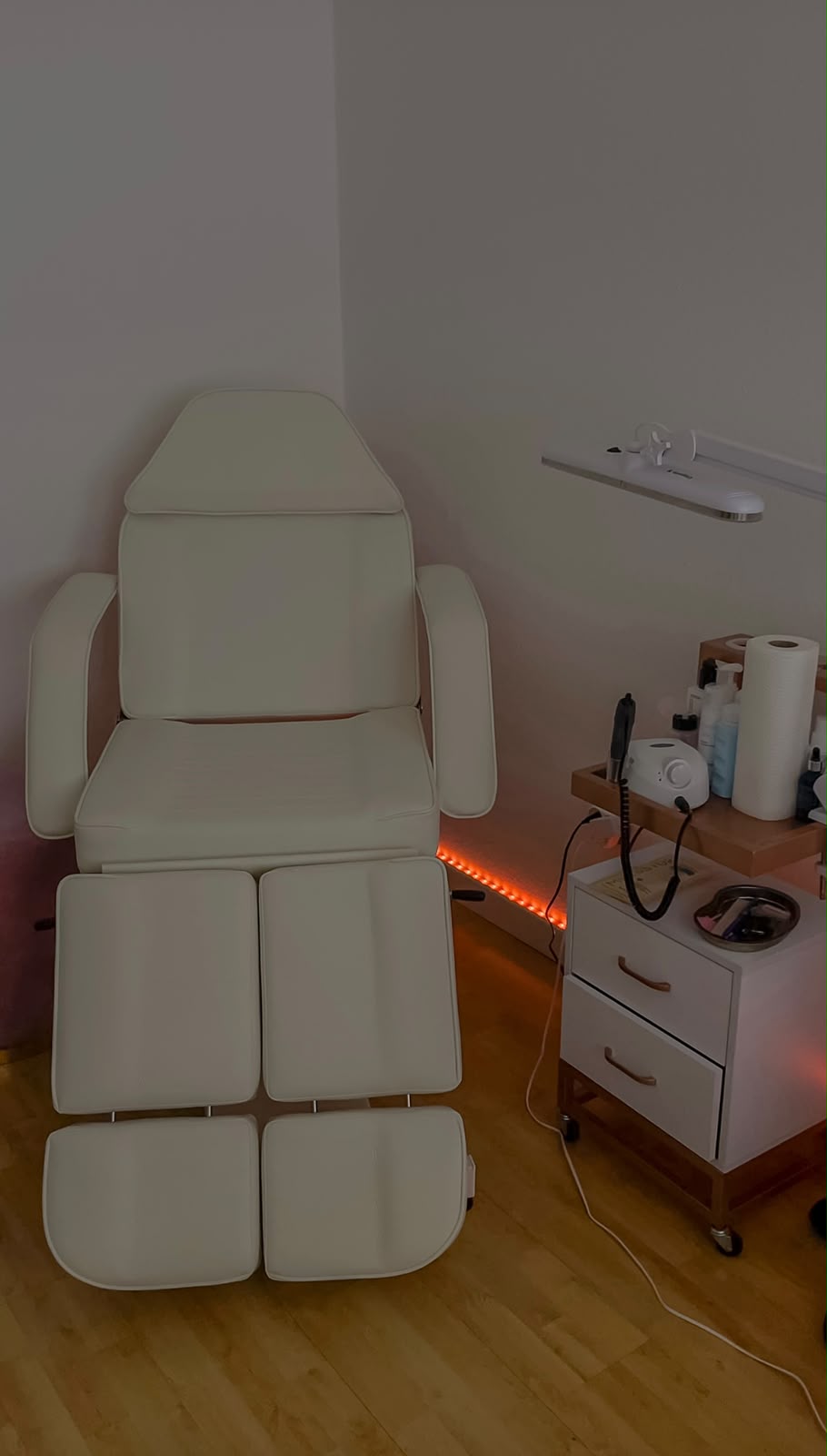 Behandlungsstuhl im Studio mit warmem Licht und vorbereitetem Arbeitswagen